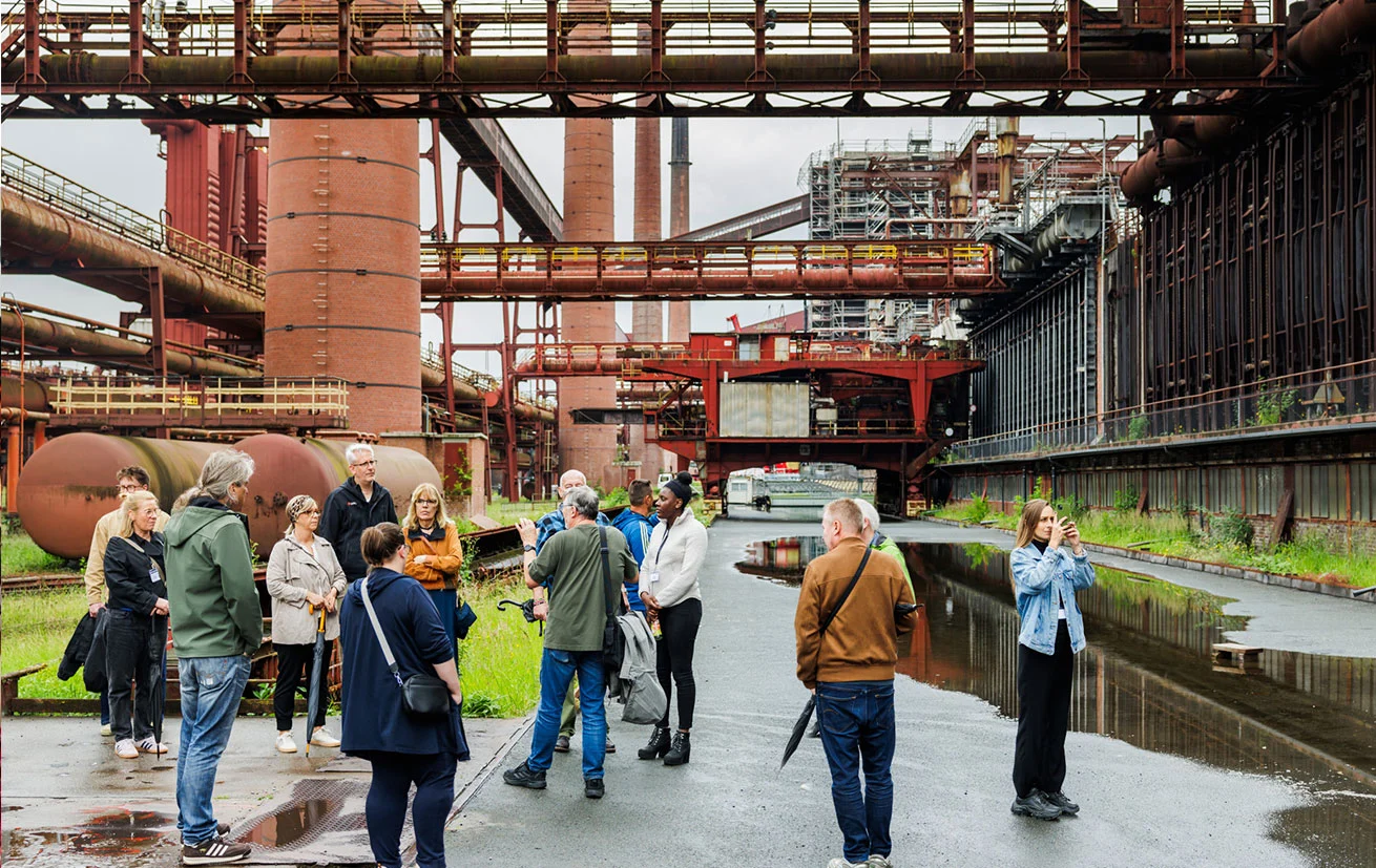 Teilnehmende der Grand Hall Erlebnistage bei einer Führung über die Kokerei Zollverein mit Blick auf die historische Industrieanlage.